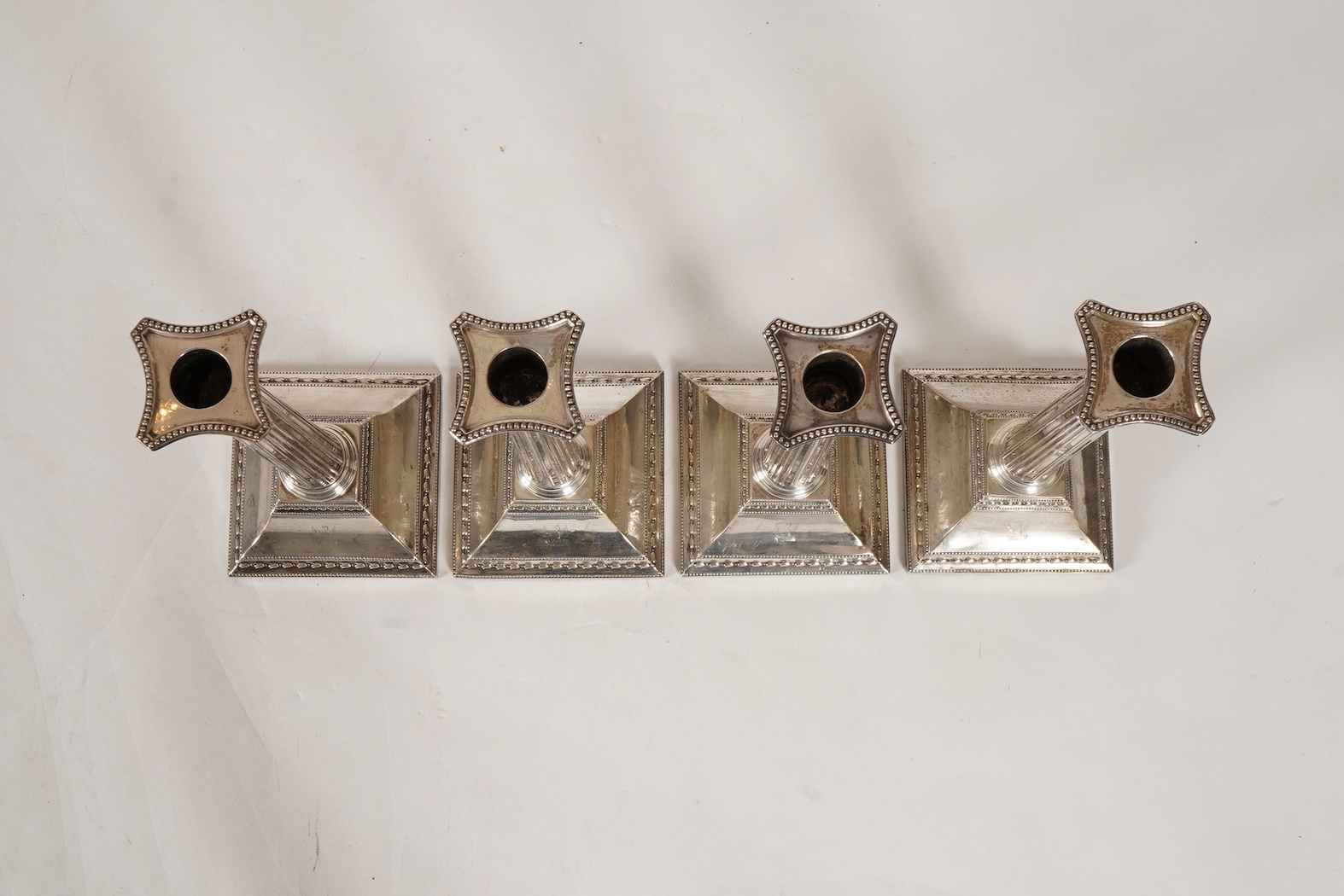 A set of four George III silver corinthian column candlesticks, by John Winter & Co